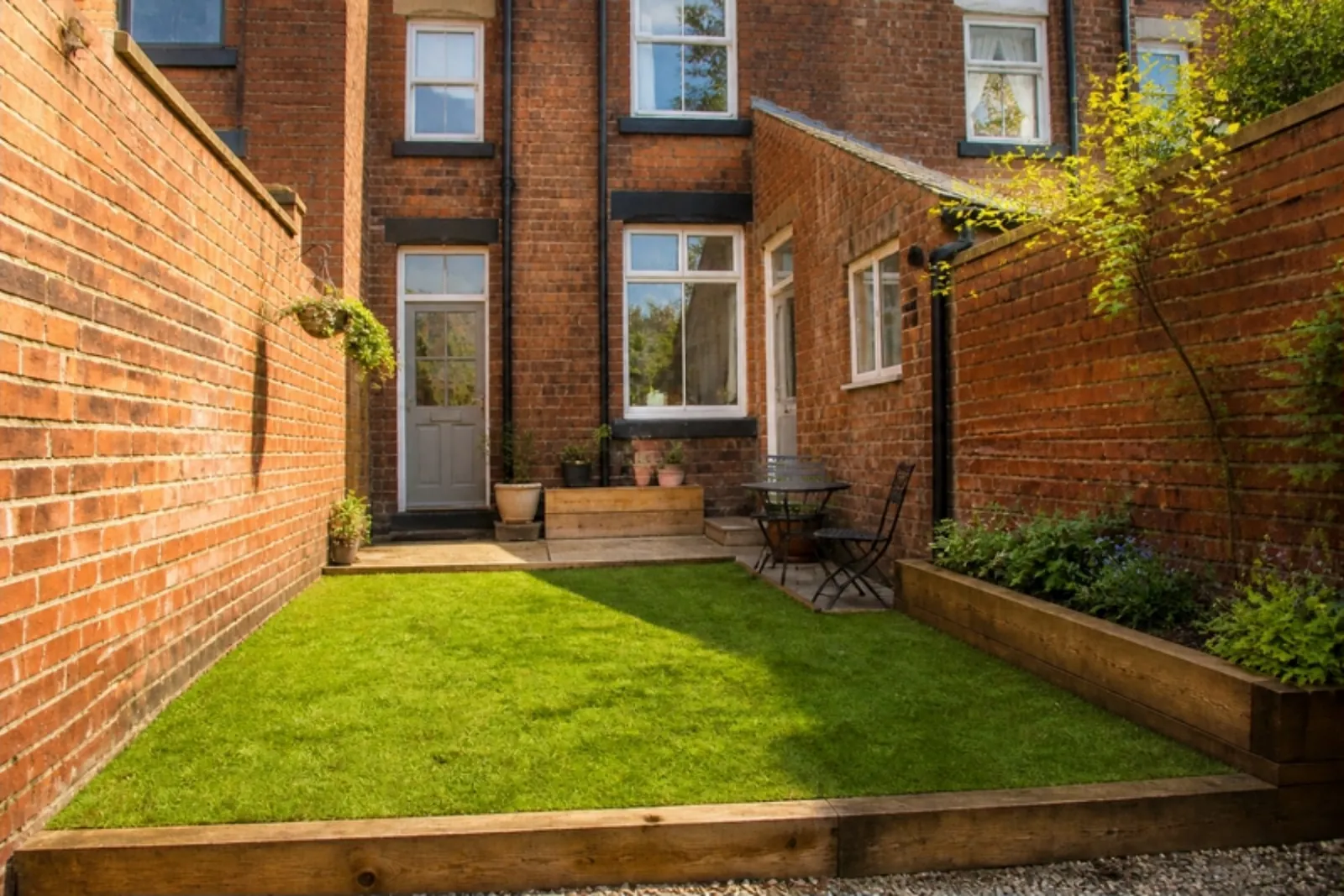 Small back garden of a red brick terrace with a fresh square of lawn in sleeper edging