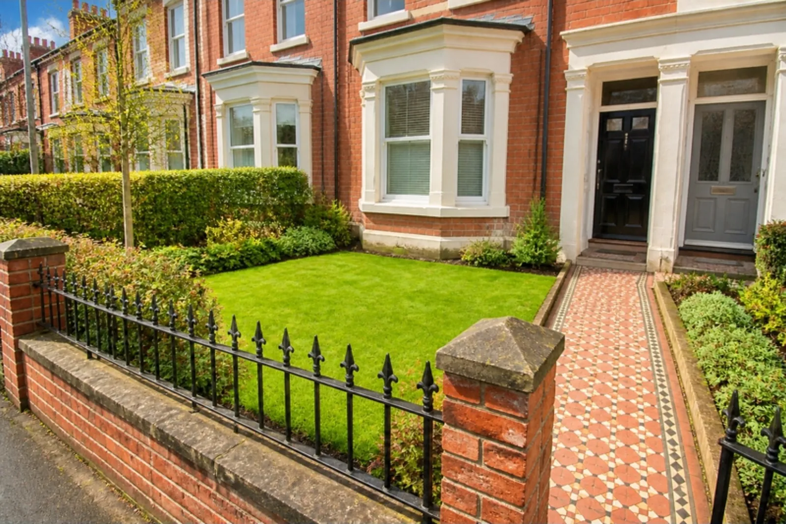Edwardian terrace front garden with a new lawn behind a low brick wall and iron railings